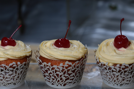 Vanilla cupcakes with butter cream frosting and a cherry on top. Party celebration, calorie