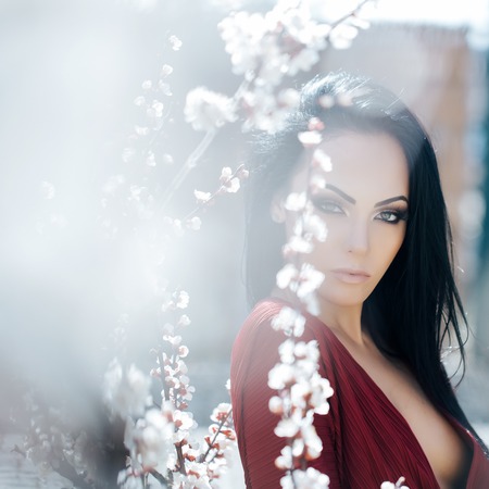Beautiful woman near apricot blooming tree. Seasonal feature, beauty and fashion.の写真素材