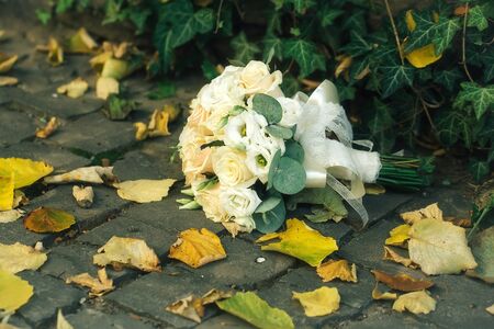 Wedding bouquet of pretty fresh roses laying on ground in autumnの写真素材