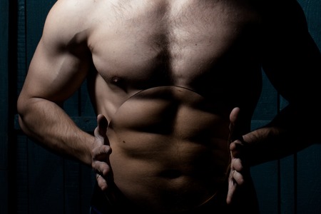 Handsome man is holding loupe and showing his muscles