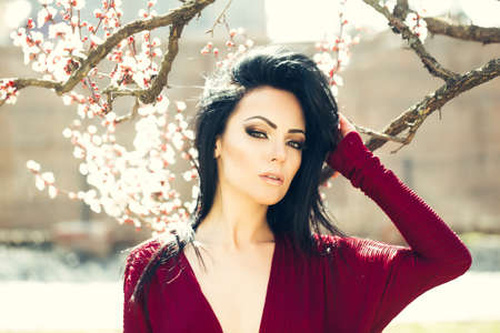 Beautiful woman near apricot blooming tree. Seasonal feature, beauty and fashion.の写真素材