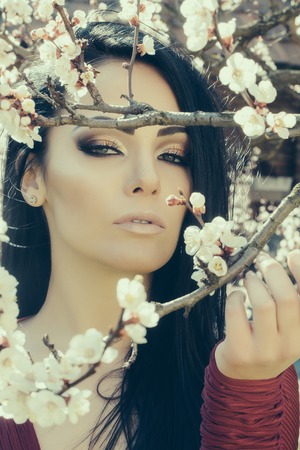 Seasonal feature, beauty and fashion. Beautiful woman near apricot blooming tree.の写真素材