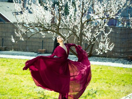 Spring fashion girl outdoors near blooming tree. Beauty Romantic woman in flowers. Sensual Lady. Beautiful Woman Enjoying Nature. Romantic beauty in fantasy orchardの写真素材
