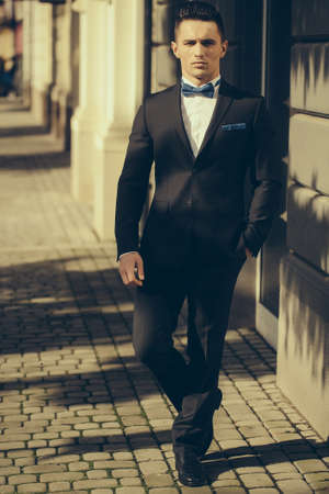 Attractive young businessman in urban background wearing suit and bow tie.の写真素材
