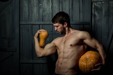 Sport and health food, Halloween gourd. Young man with muscular body and pumpkinの写真素材