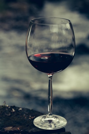 Wine glass with red wine standing on stone at seashore.の写真素材
