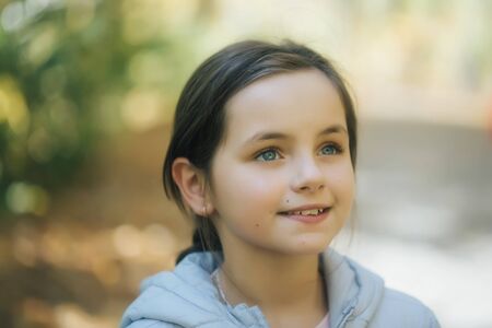 Pretty girl brunette with blue eyes and smiling face in park on natural background