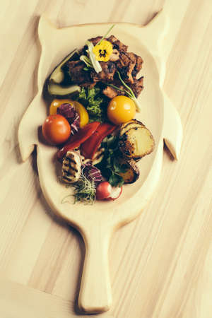 Meat with Grilled vegetables on cutting board on wooden tableの写真素材