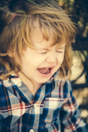 Little boy child crying outdoors in sunny summer day closeupの写真素材