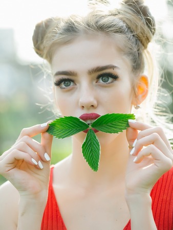 Sensual girl with fresh beautiful green young leaves outdoor in springの写真素材