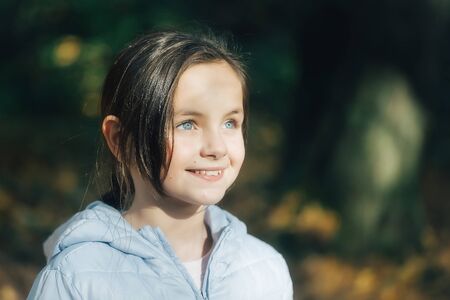 Beautiful girl with dark hair blue eyes and smiling face posing in parkの写真素材