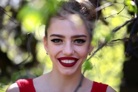 young pretty woman in the garden with fresh spring leaves on trees on blurred natural backgroundの写真素材