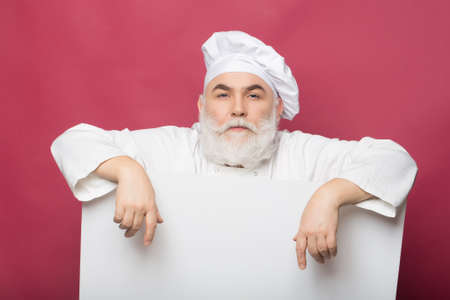 Serious cook holding blank paper on pink background, copy spaceの写真素材