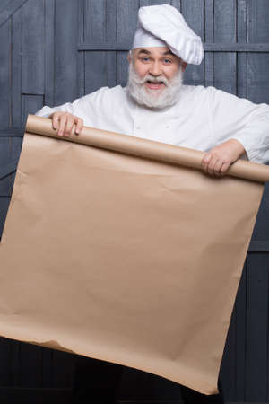 Cook holding parchment paper brown color on wooden background, copy spaceの写真素材