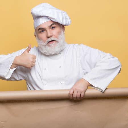 Cook holding parchment paper brown color on yellow background, copy spaceの写真素材