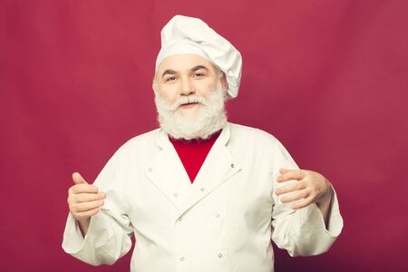 Bearded man cook in chef hat closeup in studio on pink background
