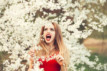 Beautiful happy young woman enjoying beauty in a flowering spring garden