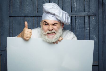 Emotional cook holding blank paper on wooden background, copy spaceの写真素材