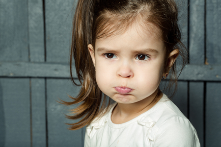 Childhood and emotions. Little girl with funny face closeup.