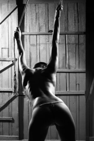 Hot naked girl is leaning forwards with the rope before her acrobatic move.の写真素材