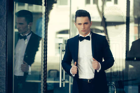 Attractive young businessman in urban background wearing suit and bow tie.の写真素材
