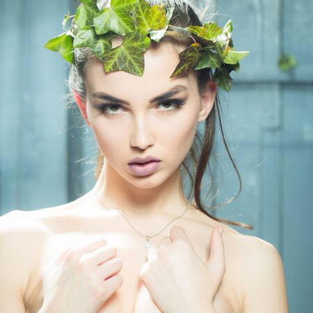 Sensual young woman with beautiful face and vine crown on head with bright makeup and bare shouldersの写真素材
