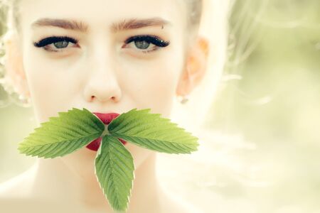 Sensual girl with fresh beautiful green young leaves outdoor in springの写真素材