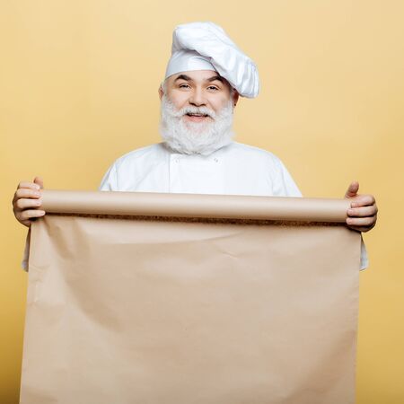Cook holding parchment paper brown color on yellow backgroundの写真素材