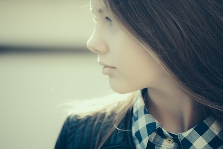 Beautiful young girl closeup with thoughtful face sunny day outdoorの写真素材