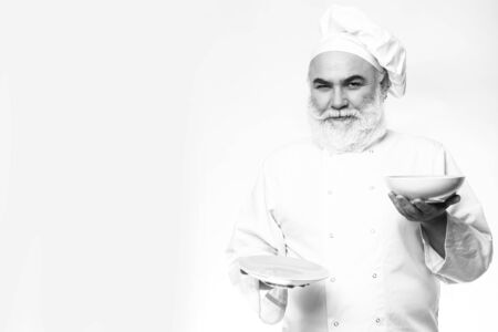 Bearded man smiling and holding plates in studio, black and white, copy spaceの写真素材
