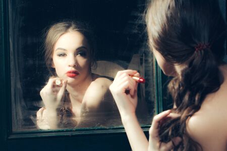 Sensual young lady with bare chest and curly hair near old dirty vintage mirrorの写真素材