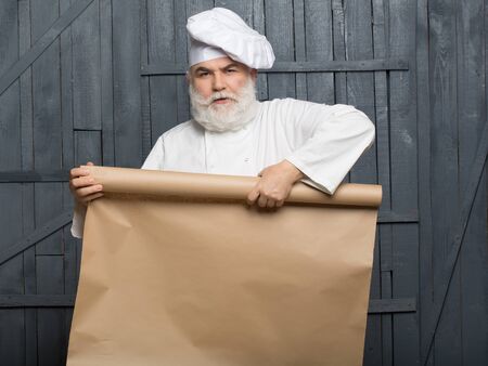 Cook holding parchment paper brown color on wooden background, copy spaceの写真素材