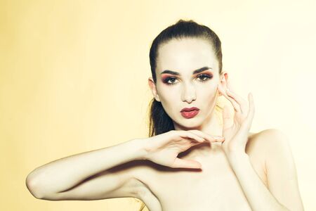 Beautiful woman model with bright makeup and hairstyle with bare body closeup in studio on yellow backgroundの写真素材