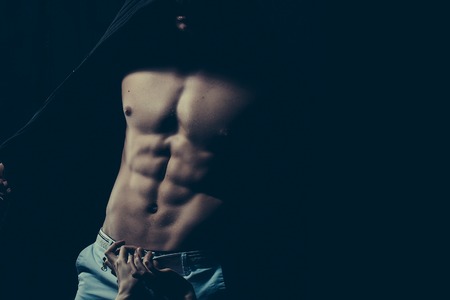 Sexy male torso with female hands on muscular body of young man