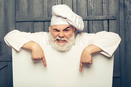 Emotional cook holding blank paper on wooden background, copy spaceの写真素材