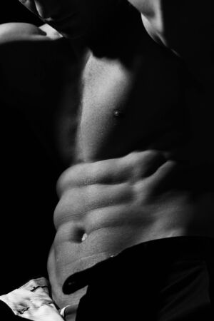 Male bare torso and sexy muscular body of young handsome man posing in studio, black and whiteの写真素材