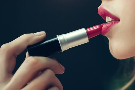 Young woman with beautiful face doing makeup with lipstick in beauty salonの写真素材