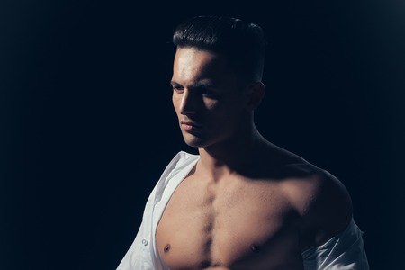 young handsome gentleman undressing fashion white shirt with sexy bare muscular torso in studioの写真素材