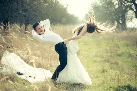 Young happy wedding couple of pretty woman and man undressing in field outdoorの写真素材