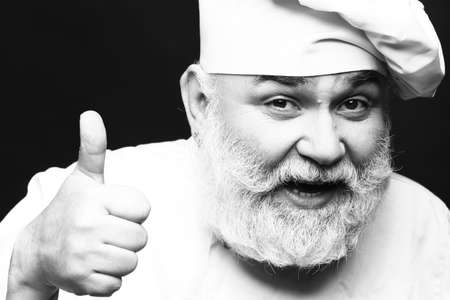 Bearded man cook with smiling face in chef hat with thumb up in studio, black and whiteの写真素材