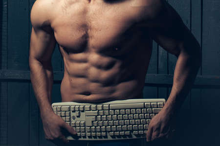 Young athletic man standing naked with keyboard.の写真素材