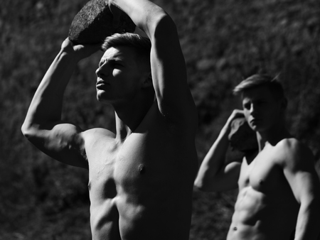 Strong men young handsome twins with sexy muscular body bare torso hold stones black and white on blurred backgroundの写真素材