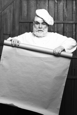 Cook holding parchment paper brown color on wooden background, copy space, black and whiteの写真素材