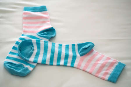 Striped socks orange and blue color lying on beige backgroundの写真素材