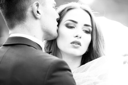Young newlywed couple of woman in wedding dress and man embracing outdoor, black and whiteの写真素材