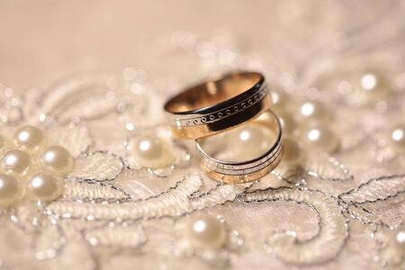 Wedding bands on white cloth richly embroidered with pearls on blurred backgroundの写真素材