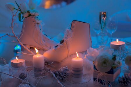White figure skates many candles white flowers and cones decor in dark lightの写真素材
