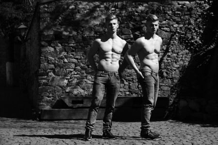 black and white. Twin brothers young sensual serious with bare chest in jeans pose outdoorの写真素材