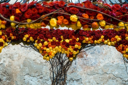 Floral arrangement with colorful rose flowers and wooden twigs on open garden house near old white buildingの写真素材