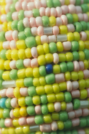 Fragment of easter egg decorated with colorful seed beads on blurred background